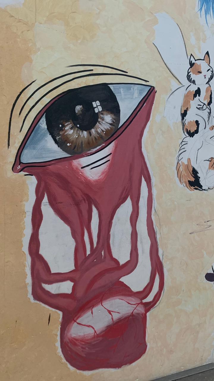 O olho, com pupila marrom e reflexo branco, é estilizado com pálpebras claras. Em vez de lágrimas, o olho está chorando um fluido vermelho-escuro, que se esvai com formas orgânicas e venosas, terminando em uma massa que se assemelha a um coração sangrando ou um órgão na parte inferior.