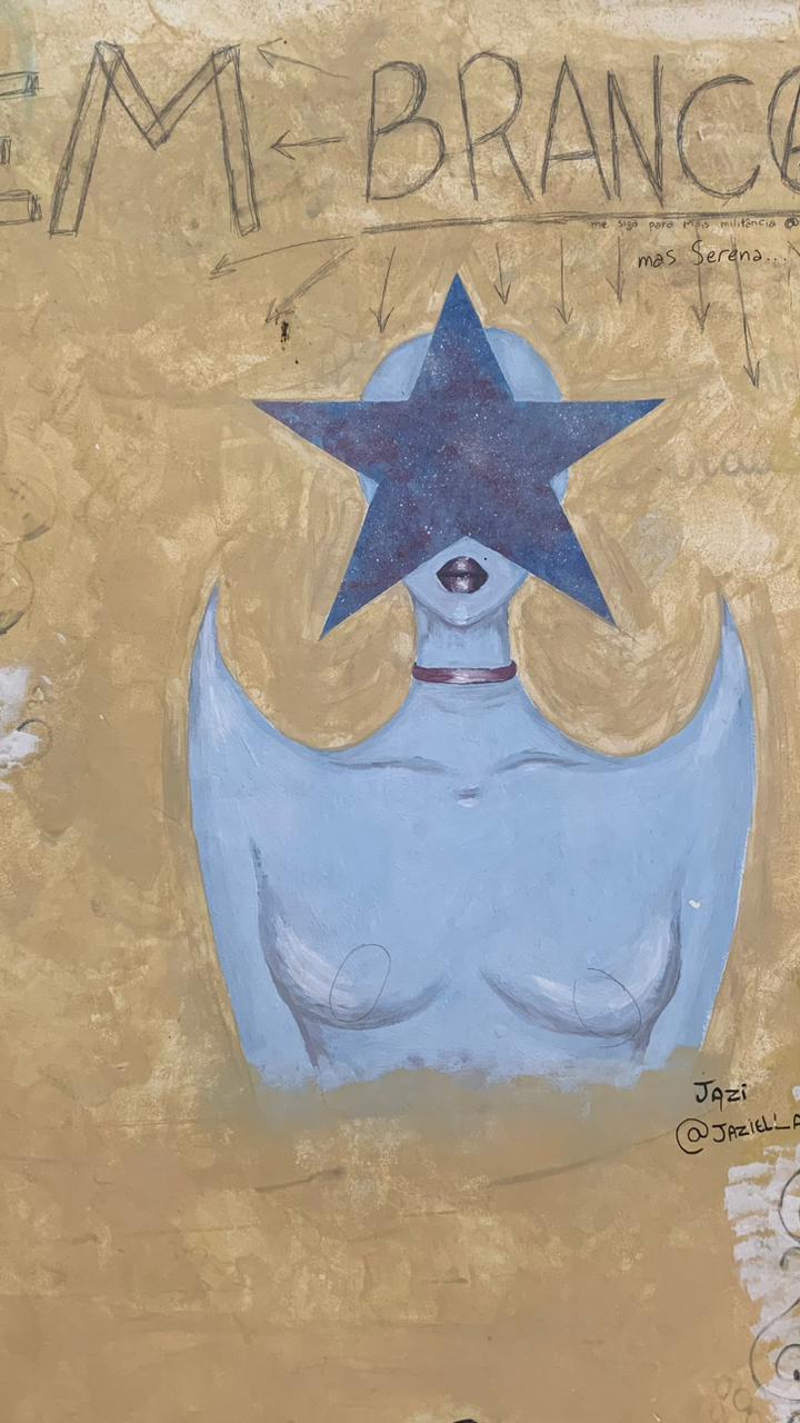 Pintura em uma parede com fundo em tons de amarelo e bege. A figura central é um busto feminino com a pele em tom azul-claro, usando um choker vermelho no pescoço. O rosto é coberto por uma grande estrela de cinco pontas, pintada em azul-escuro com textura que lembra o céu noturno. A boca da figura, com lábios escuros, está visível abaixo da estrela. Há um contorno sutil de asas arredondadas saindo dos ombros.