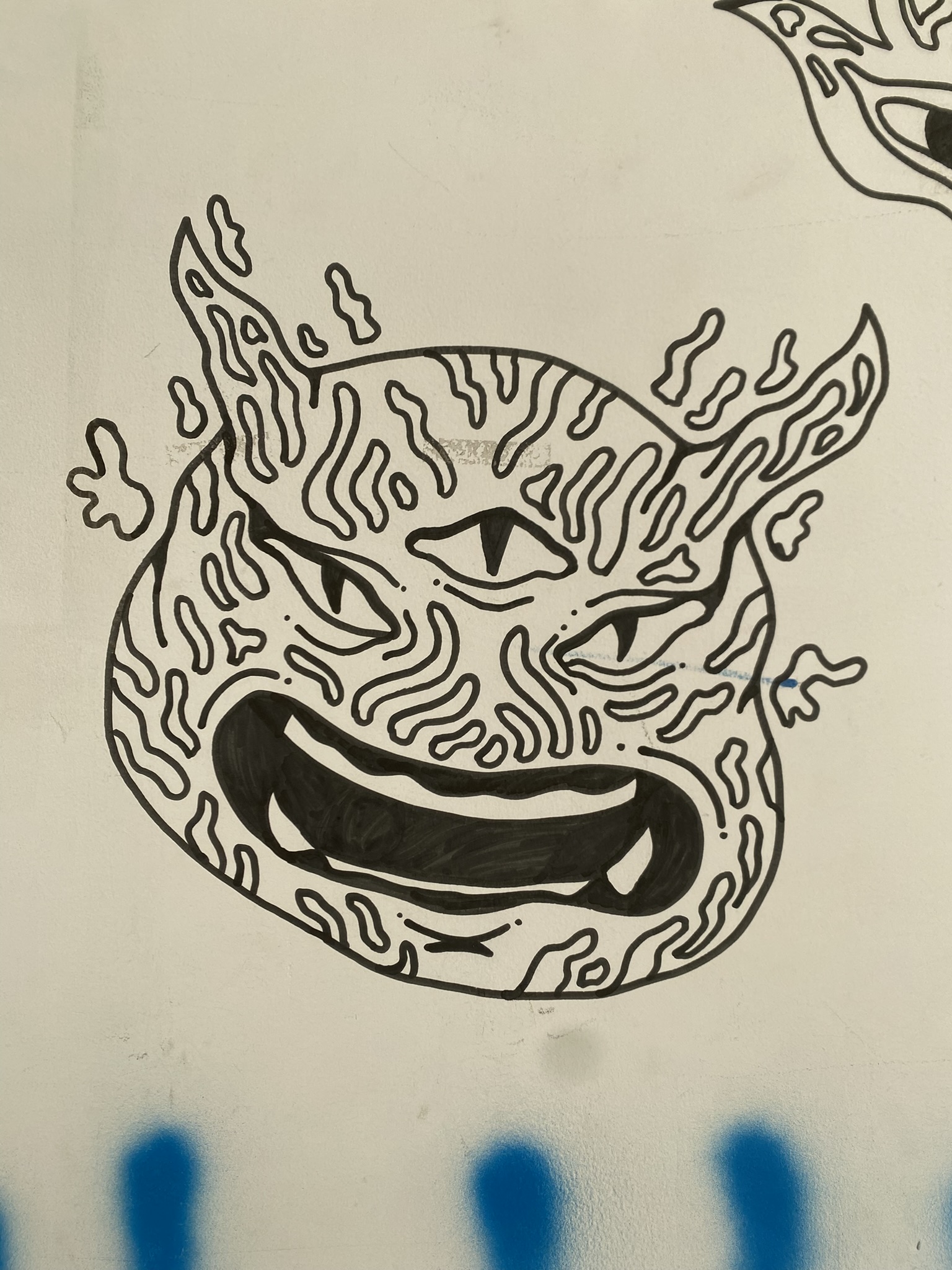 A imagem retrata o desenho em traços pretos de uma cabeça de criatura com três olhos, chifres e uma boca aberta exibindo dentes. Toda a superfície da figura é preenchida por padrões ondulados e orgânicos que lembram impressões digitais, destacando-se sobre o fundo branco.